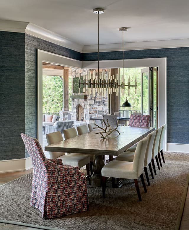 Dining Room in N. Raleigh Model Home w/ Teal grasscloth, large dining table, accent host chairs, modern chandelier, and sisal rug - looking onto open outdoor area