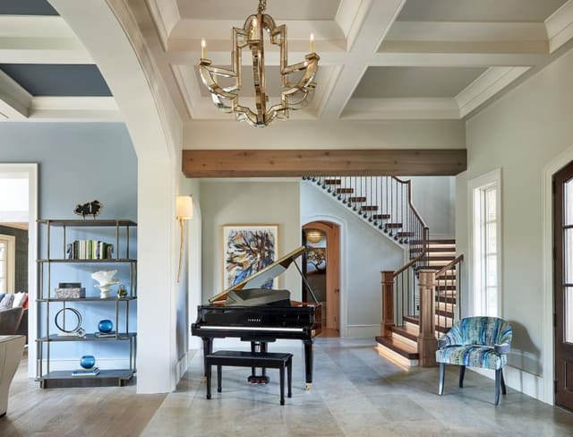 Foyer in N. Raleigh Model Home featuring mirrored chandelier, Grand Piano, and staircase w/ lit risers