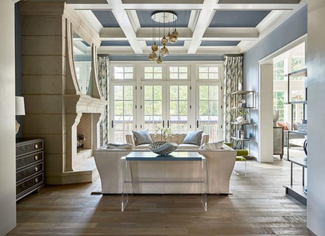 Foyer looking into Living Room of Model Home featuring wide plank wood floors, acrylic console, custom window treatments, cream leather sofas and twin etageres.