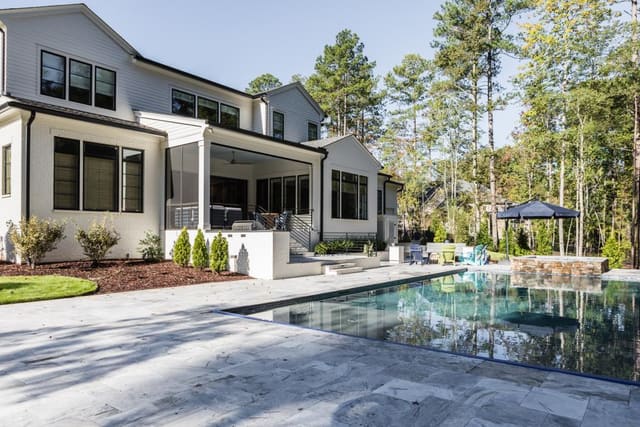 Exterior of white painted brick home with pool and screened porch