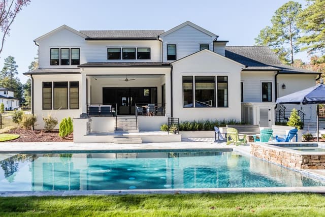 Rear Exterior of white painted brick home with pool and screened porch