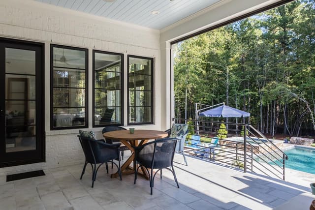 Back porch of N. Raleigh home with teak table, wicker dining chairs, overlooking pool