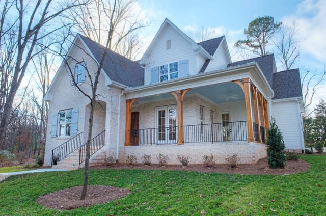 Exterior of North Raleigh home with white brick, blue shutters, blue porch ceiling, and natural wood columns.