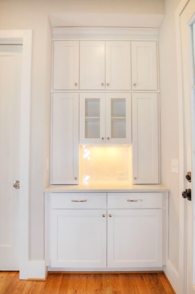 Small bar with white cabinets, white backsplash, and white quartz countertops.