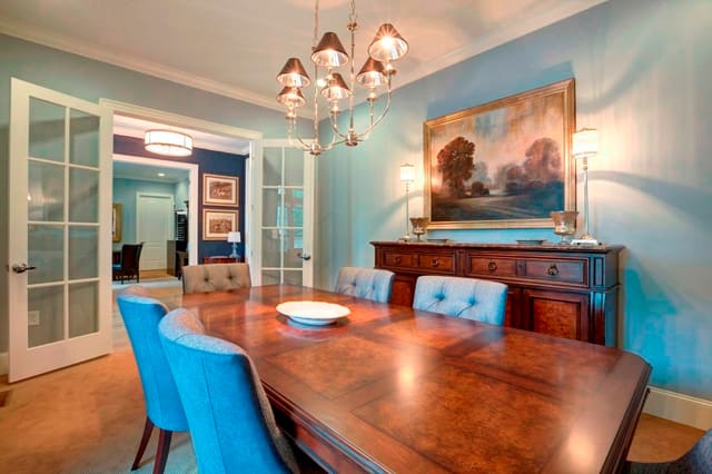 Conference Room in clubhouse with blue walls, upholstered dining chairs, burled wood dining table and credenza, and chrome chandelier