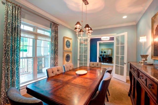 Conference Room in clubhouse with blue walls, navy and ivory damask drapery panels, upholstered dining chairs, burled wood dining table and credenza, and chrome chandelier