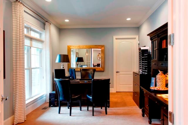 Office in clubhouse with striped drapery panels and dark wood desk and bookcase