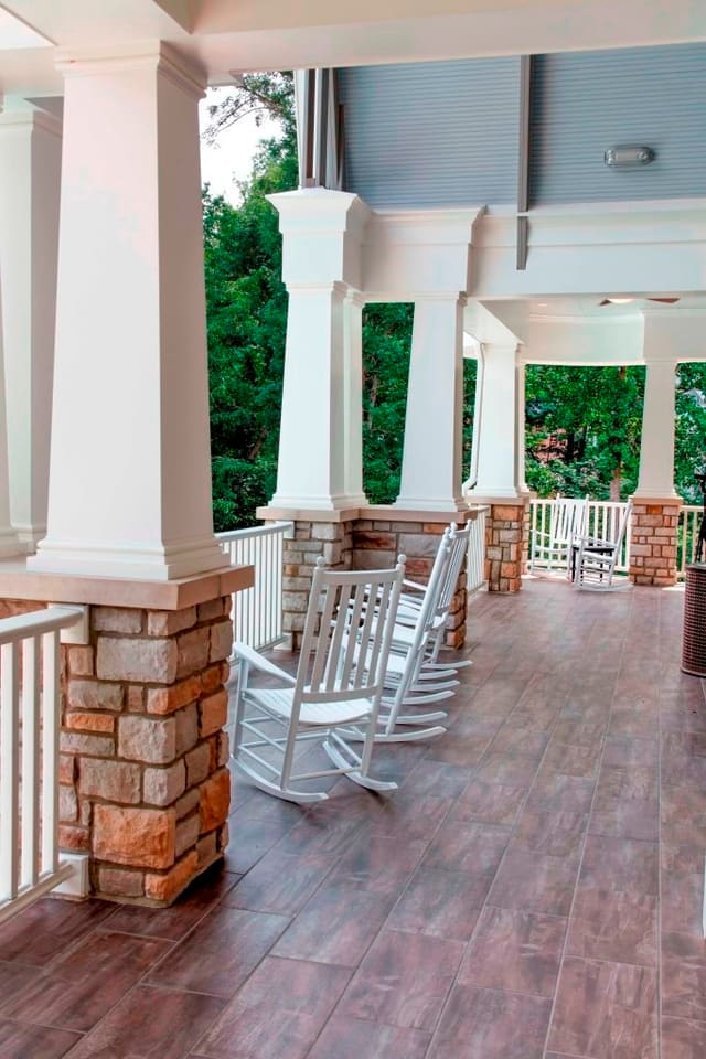 Covered porch with rocking chairs and stone base columns at Raleigh clubhouse