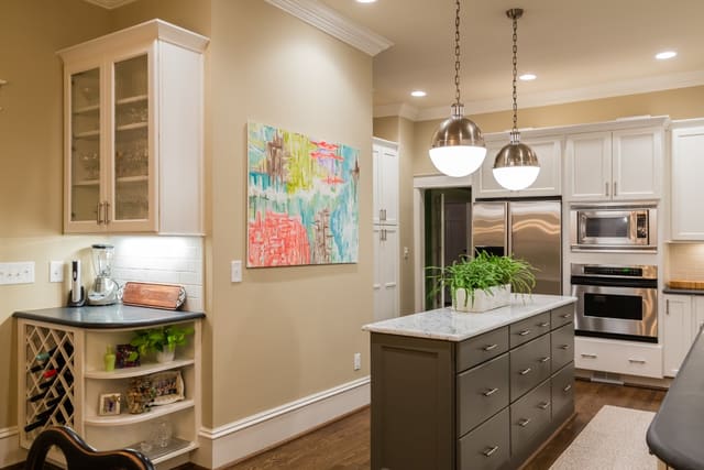 Remodeled Kitchen with white subway tile, white cabinets, contrasting island, and large pendants.