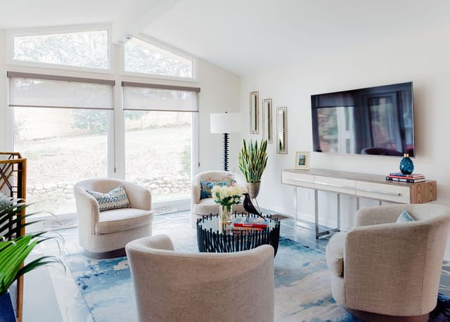 Family Room featuring teal abstract area rug, 4 swivel chairs, blackened iron coffee table and stainless steel base console.