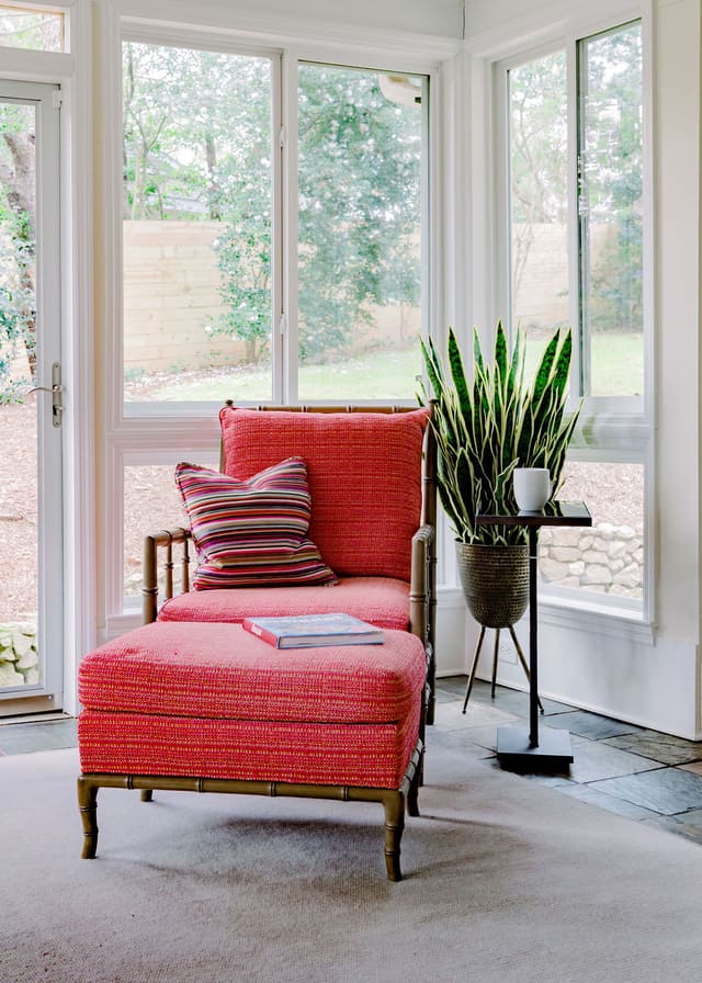 Sun Room with neutral area rug and matching fuschia chair and ottoman.