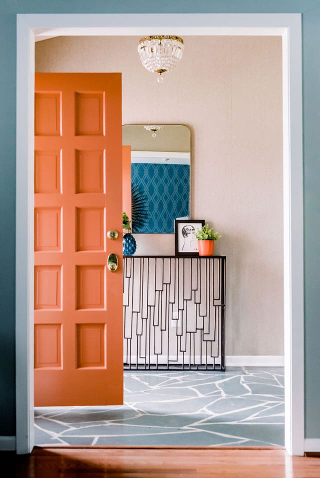 Entryway to Mid-Century Modern home featuring original slate flooring and light, with added banded brass mirror and bronze console table.