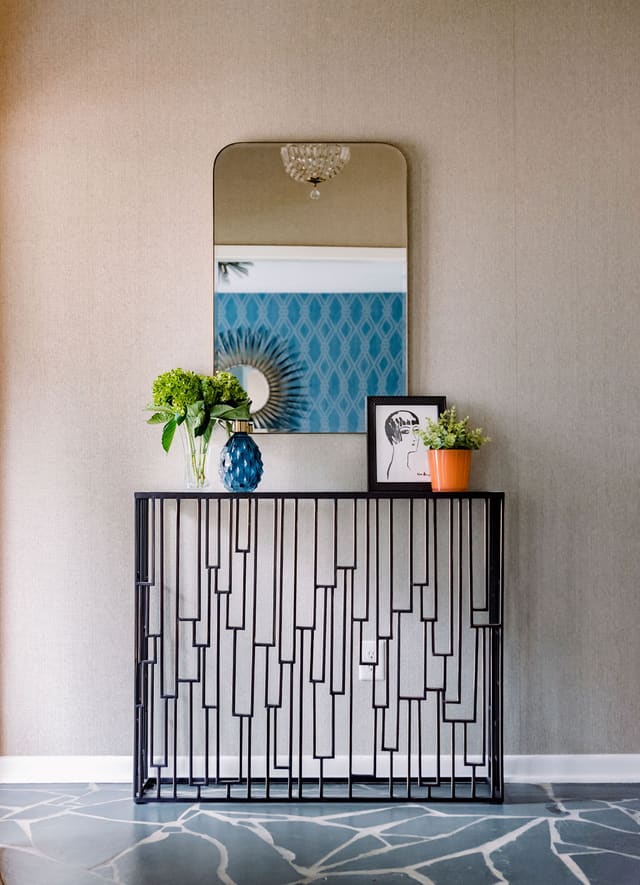 Entryway to Mid-Century Modern home featuring original slate flooring and light, with added banded brass mirror and bronze console table.