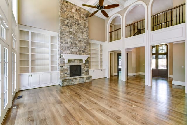 Living Room of Raleigh Home with 2-story stone fireplace, built-in bookshelves and arched openings in balcony