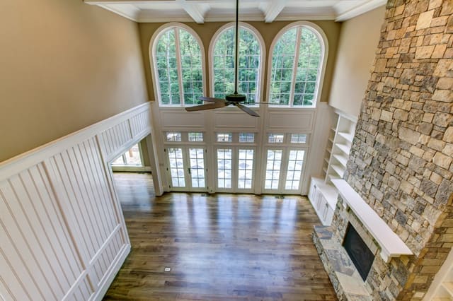 Living Room of Raleigh Home with 2-story stone fireplace, white wood paneling and arched windows
