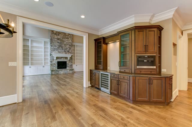 Kitchen looking into Family Room in Raleigh Home, showing 2-story stone fireplace and bar