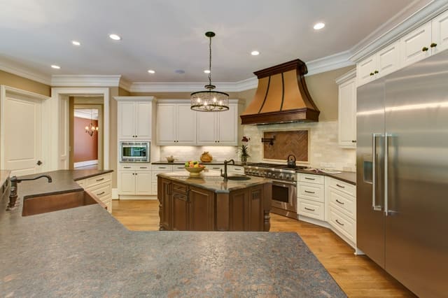 Raleigh Kitchen with white cabinets, chandelier, and custom range hood