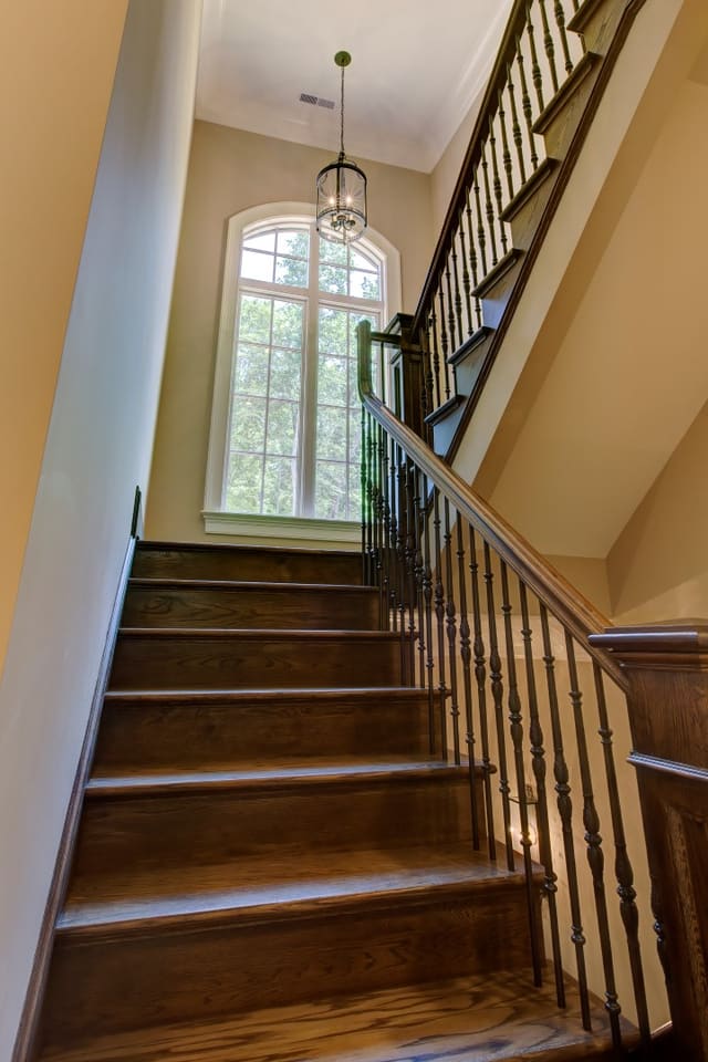 Staircase in Raleigh home with arched window in landing