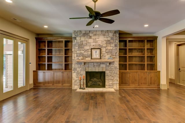 Basement of Raleigh home with stone fireplace and built-in bookshelves