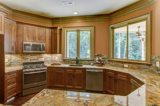 Basement Kitchen in Raleigh home with granite countertops and natural tile backsplash