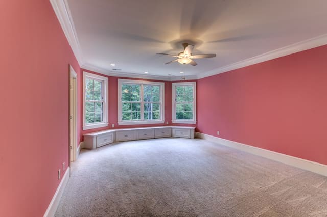 Girls bedroom in Raleigh Home with coral walls and built-in drawers under bay window