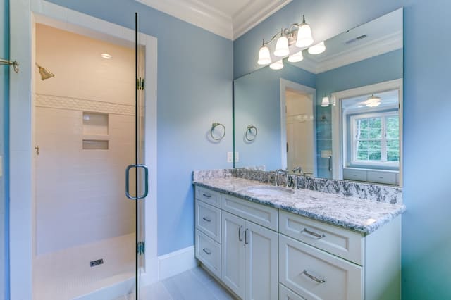 Kids' Bathroom in Raleigh home with blue painted walls, granite countertops, and white subway tile shower