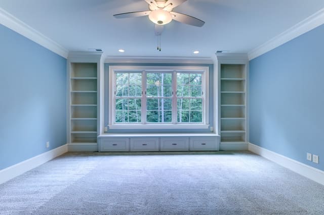 Bedroom in Raleigh home with blue painted walls and built-ins around window