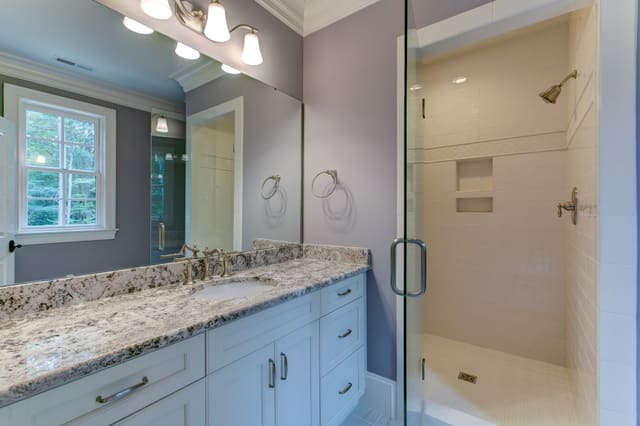 Kids' Bathroom in Raleigh home with purple painted walls, granite countertops, and white subway tile in shower