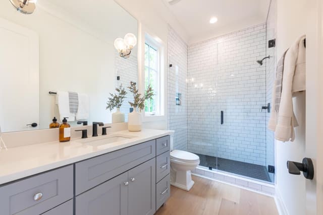 Bathroom with white brick shower wall and grey cabinetry