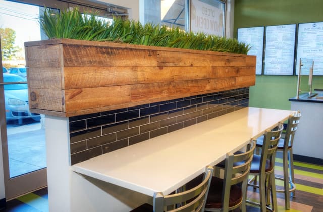 Interior of Diced Restaurant in Raleigh with custom designed greenery box above bar with black backsplash and white quartz top