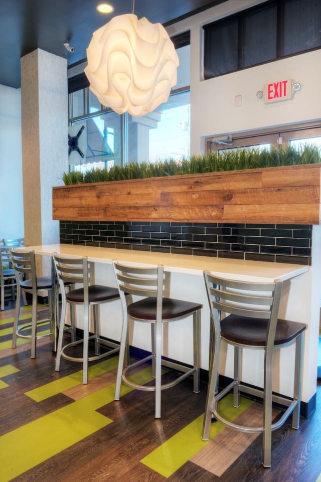 Interior of Diced Restaurant in Raleigh with custom designed greenery box above bar with black backsplash and white quartz top