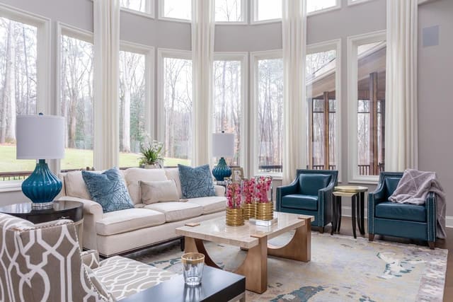 Open concept family room filled with sofa, chairs, cocktail table, fireplace, and decorated bookshelves.