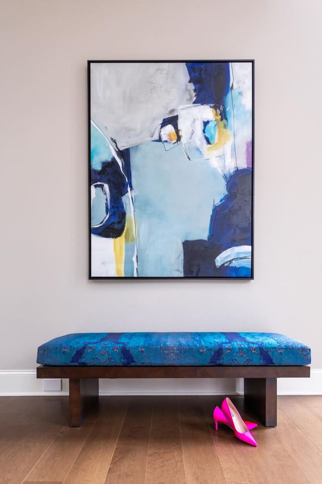 Abstract art placed over an upholstered bench in the foyer.