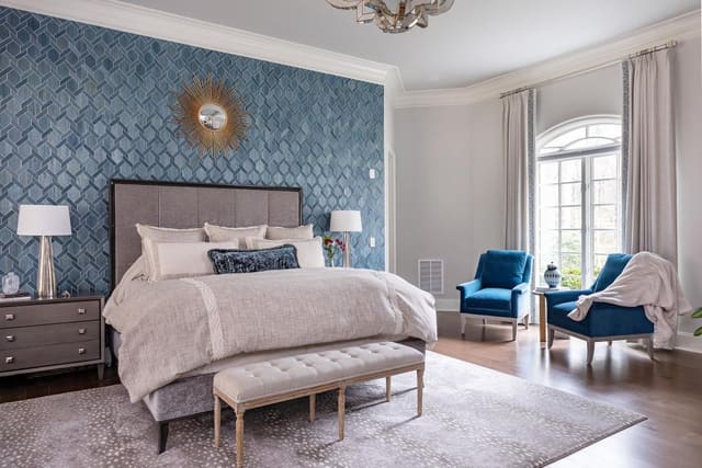 Master bedroom with textured wallpaper, upholstered king bed, matching bedside tables, and lamps.