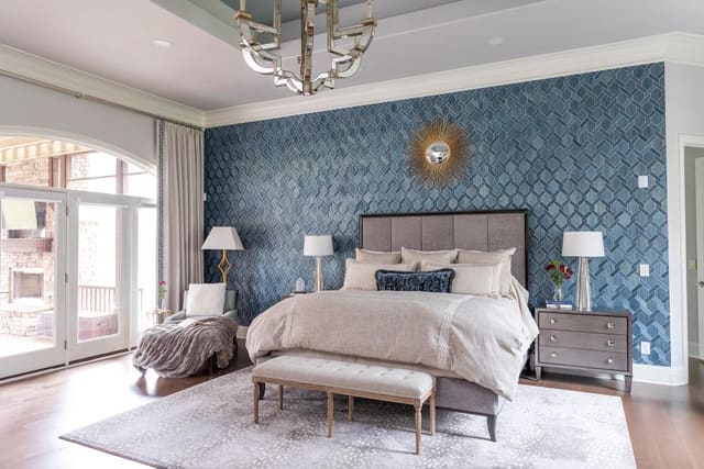 Master bedroom with textured wallpaper, upholstered king bed, matching bedside tables, and lamps.