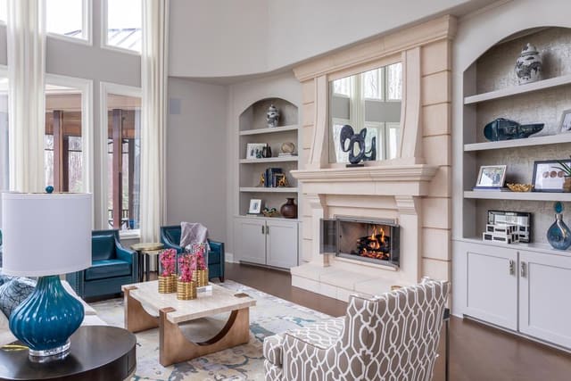 Family room filled with sofa, chairs, cocktail table, fireplace, and decorated bookshelves.