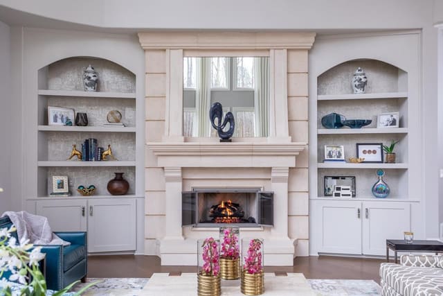 Family room filled with sofa, chairs, cocktail table, fireplace, and decorated bookshelves.