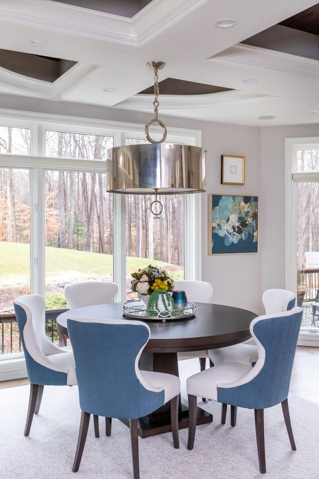 Breakfast room table and upholstered chairs with silver fixture above.