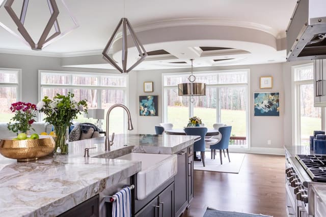 Kitchen with silver lighting fixtures, a marble countertop, and fresh flowers.