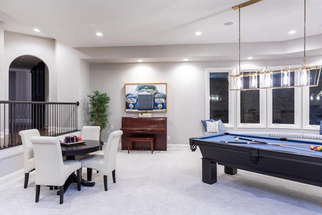 Game room including a pool table, game table and chairs, piano, and window seating.