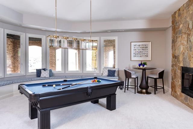Game room including a pool table, game table and chairs, piano, and window seating.