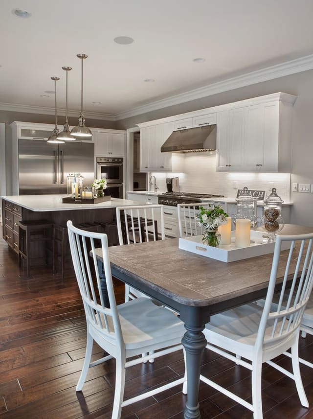 Kitchen in Wake Forest Home with white cabinets, large island, and stainless steel appliances and fixtures