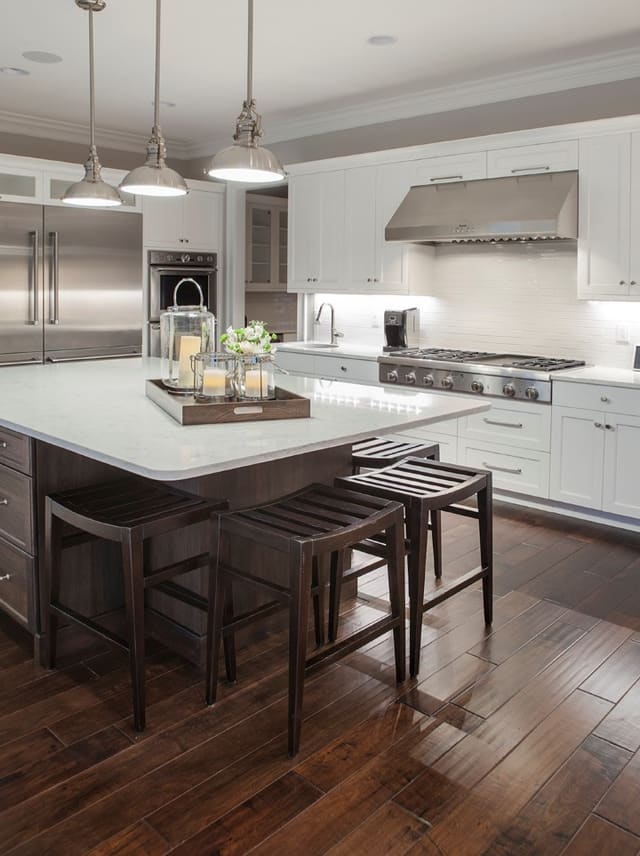 Kitchen in Wake Forest Home with white cabinets, large island, and stainless steel appliances and fixtures