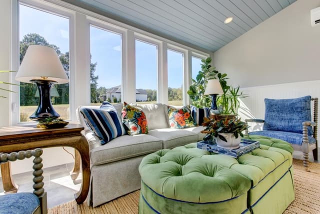 Sun Room with 3 piece ottoman, colorful pillows, and blue chairs and lamps