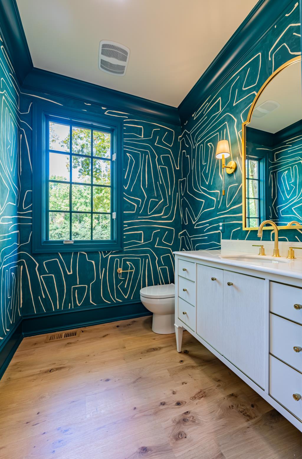 Bold powder room design with patterned wallpaper by Design Works Studio