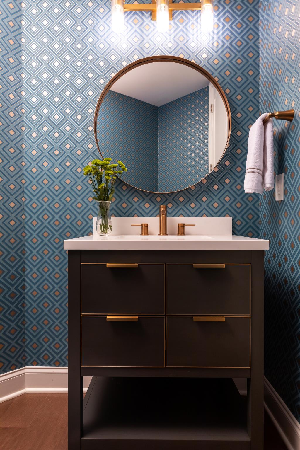 Powder bath with decorative cabinet, countertop, and patterned wallpaper.